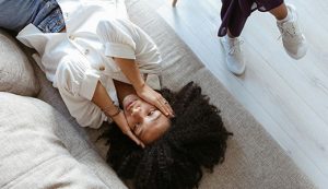 Une femme allongée sur un canapé, la tête entre ses mains